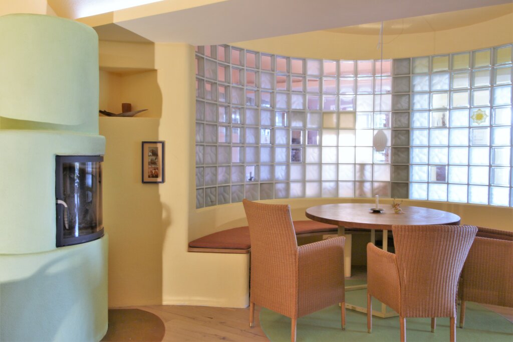 Innenraumansicht auf Ofen und Sitzbereich vor Glasbausteinwand.